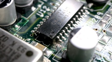 Closeup of a Sony CXA1145 Video Encoder chip. The first pin is cut off, and the PCB underneath is damaged.
